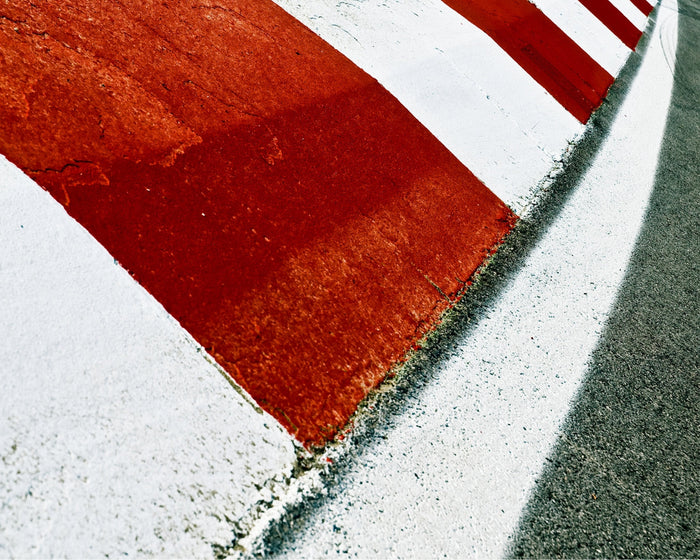 Close-up of a racing curb in red and white, showing the mark of speed and motion.