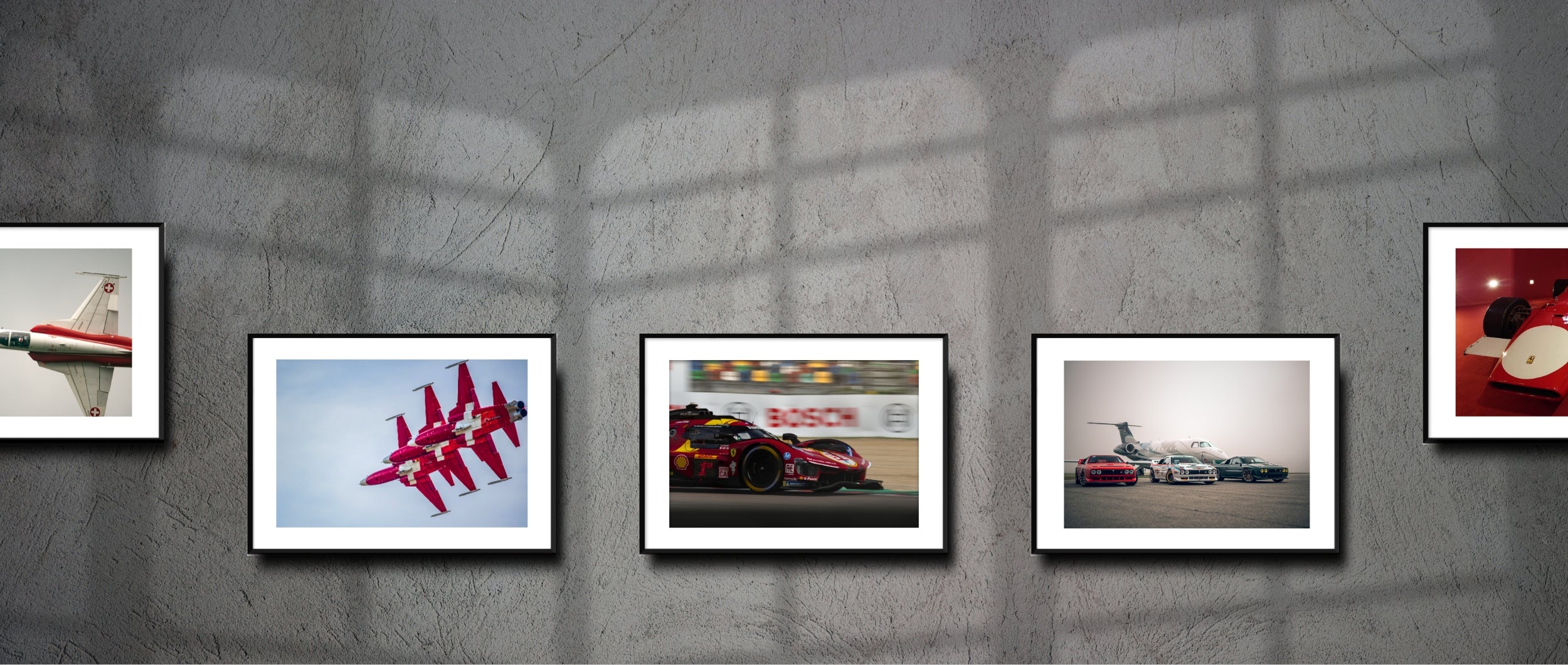 Gallery wall with framed fine art prints featuring aviation and automotive icons — from aerobatic jets and endurance racing Ferraris to vintage supercars and F1 legends.